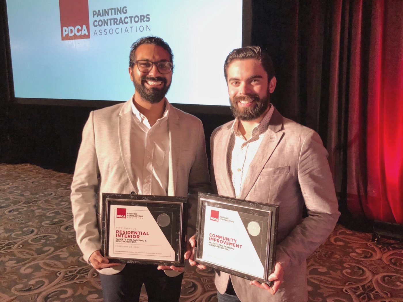 Two team members holding PDCA Residential Interior and Community Improvement award plaques