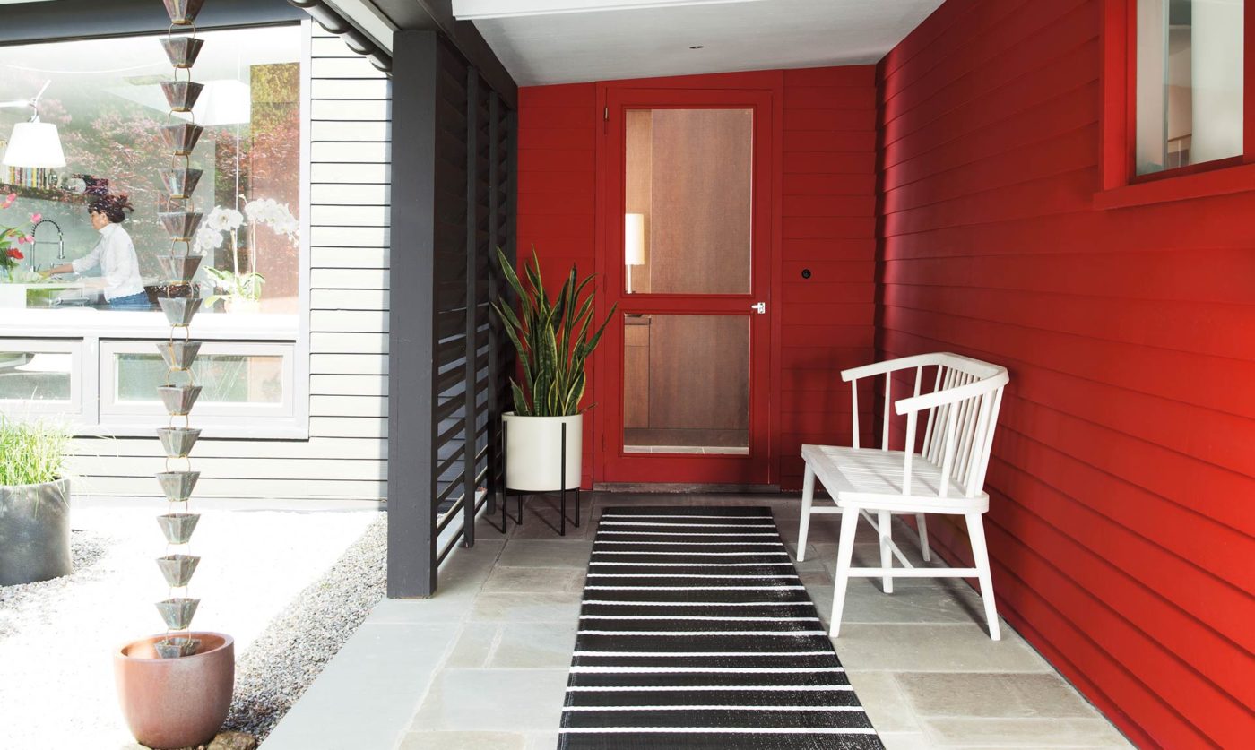Front entry with siding and door in Benjamin Moore's 2018 color of the year, a deep red, and a white bench