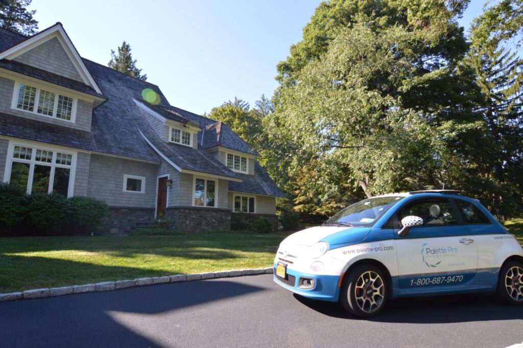 Blue and white Palette Pro company car parked in front of a large gray shingled house