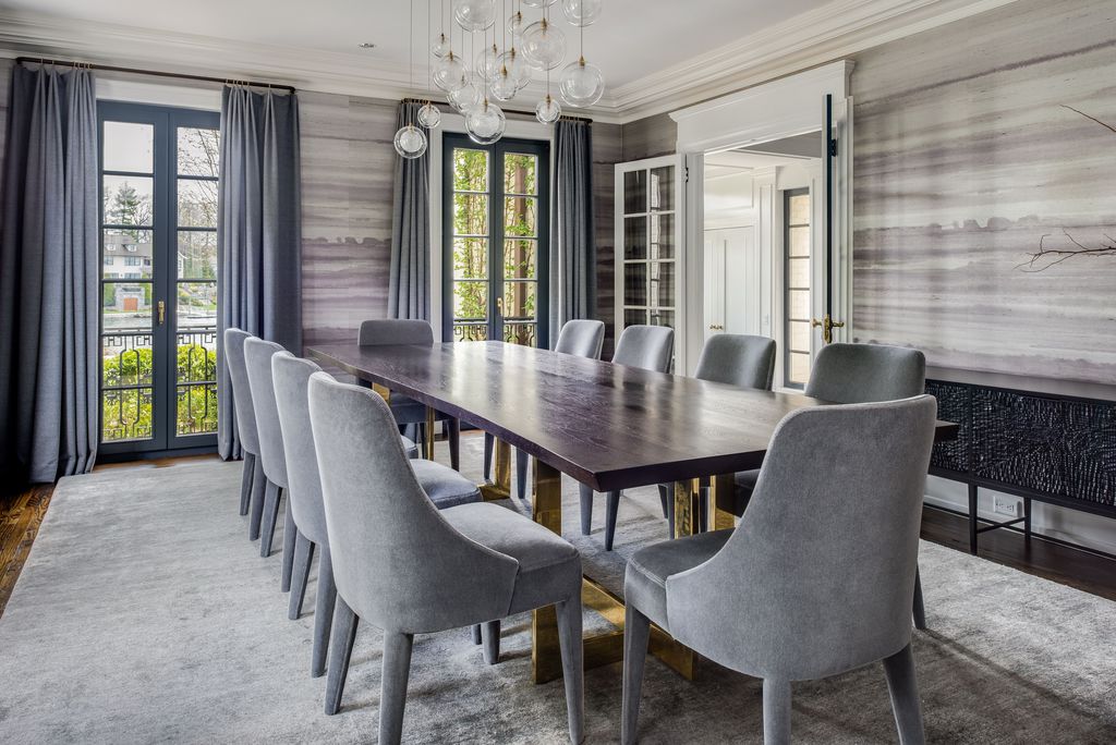 Dining room with a long dark wood table, gray velvet chairs, gray drapes, French doors and a glass globe chandelier