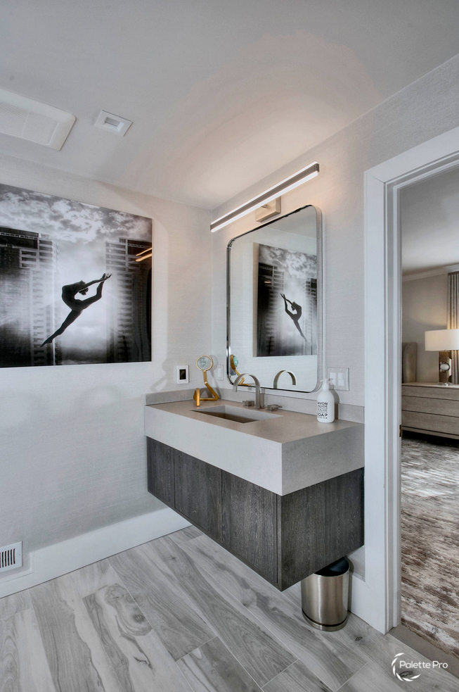 Bathroom with a floating gray wood vanity, a stone countertop, a light bar over the mirror and black and white dancer art