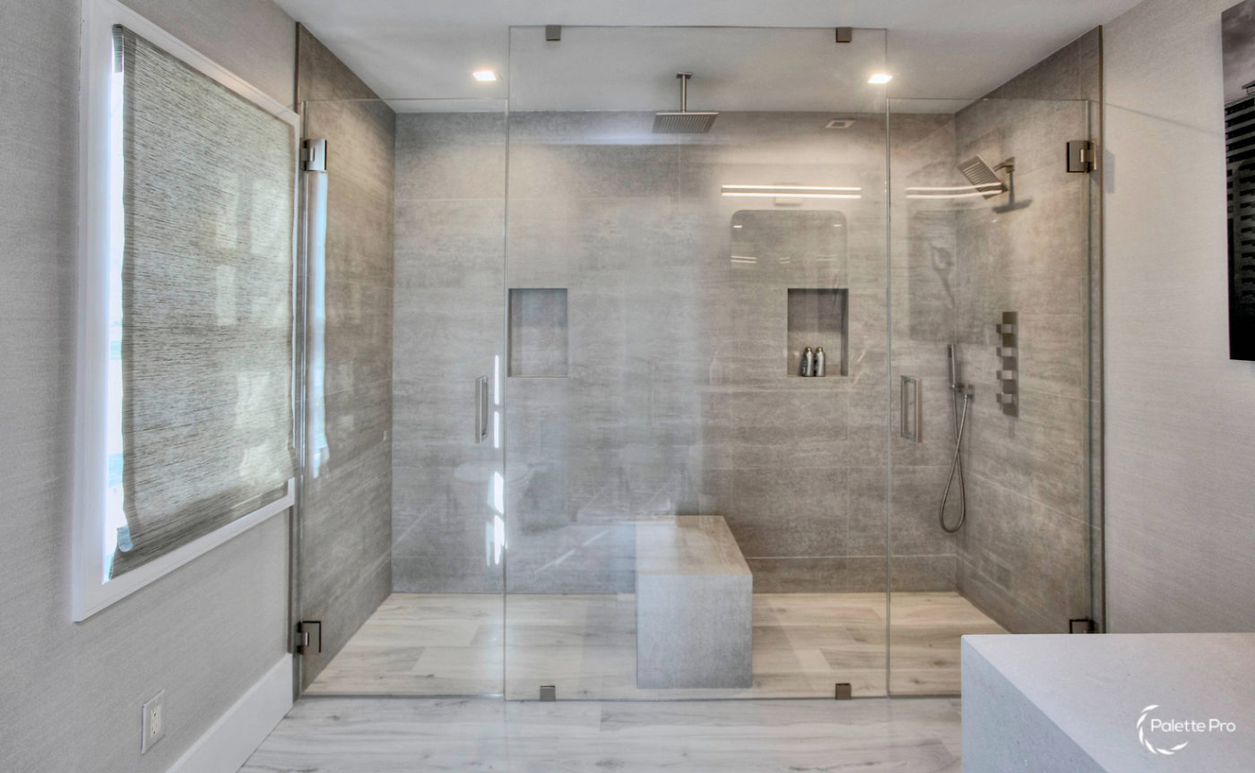 Large glass walk-in shower with gray stone tile, a built-in bench, wall niches and a ceiling rain shower head