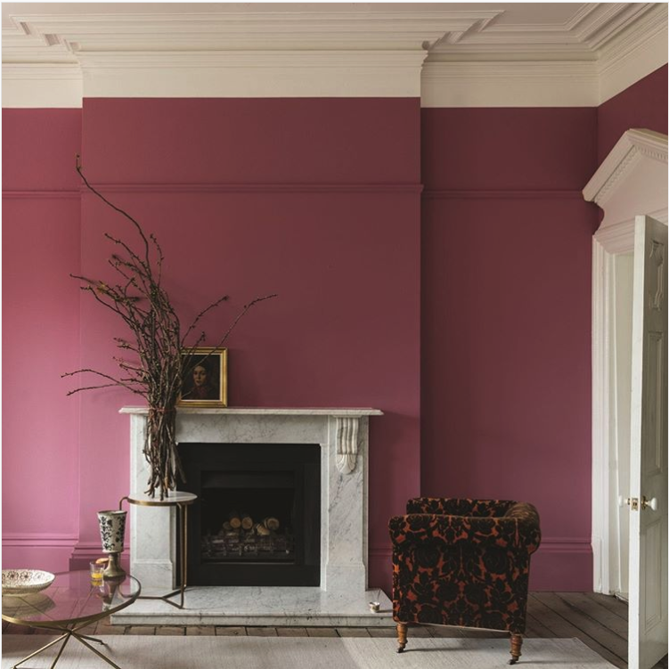 Living room with raspberry pink walls, white crown molding, a white marble fireplace and a dark floral armchair