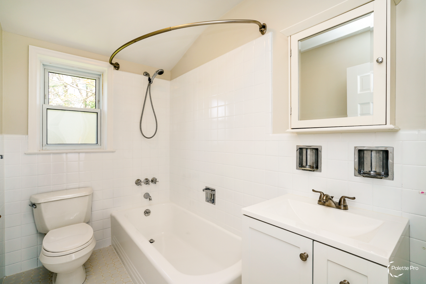 Bathroom with reglazed white wall tile and tub, a curved shower rod, a white vanity and medicine cabinet