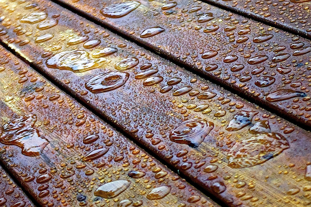 Close-up of water beading on stained wood deck boards