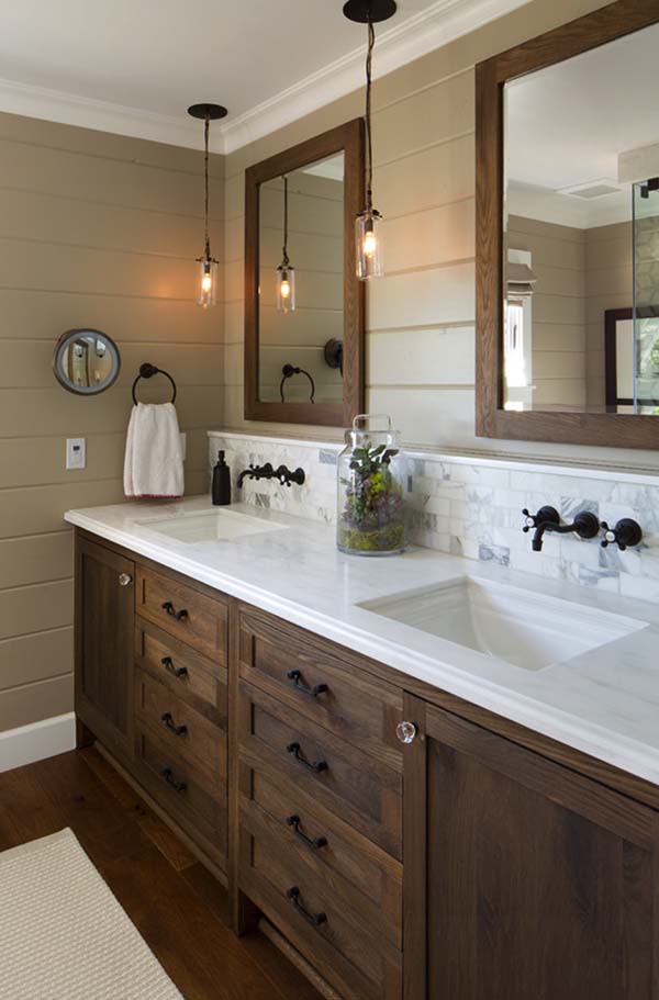 Bathroom with taupe shiplap walls, a wood double vanity, a white marble top and wall-mounted black faucets