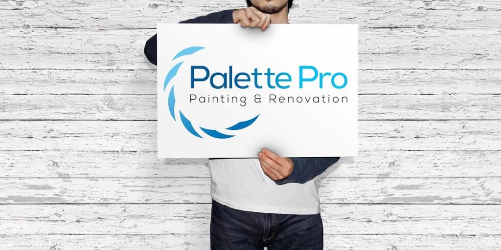Person holding a white sign with the Palette Pro Painting & Renovation logo in front of a whitewashed wood wall