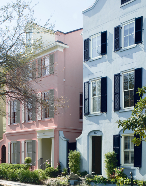 Pink townhouse with gray green shutters beside a pale blue townhouse with black shutters