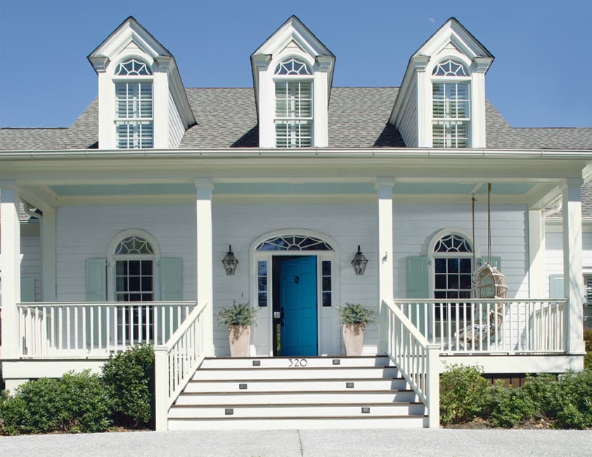 White house with three dormers, a wide front porch, sea green shutters and a turquoise front door
