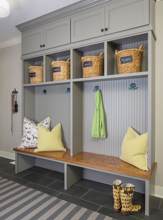 Gray mudroom built-in with upper cabinets, wicker basket cubbies, beadboard backs, coat hooks and a wood bench
