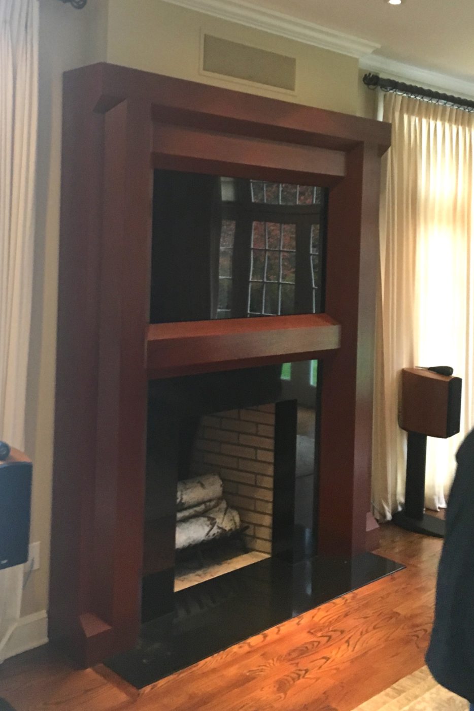 Fireplace with a tall dark red wood surround, a TV built into the upper frame and birch logs in the firebox