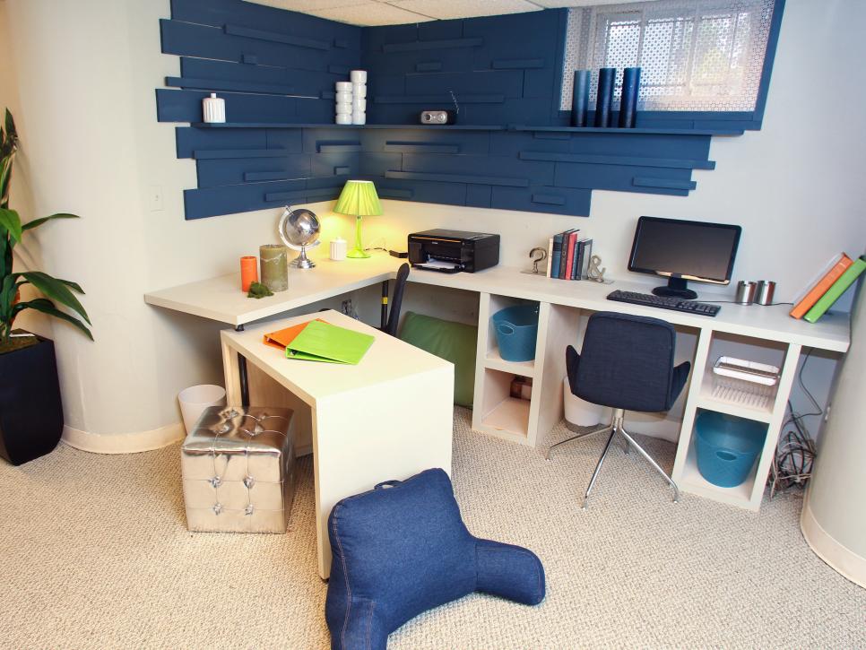 Basement office with a white L-shaped desk, cube storage and navy blue wood slat shelving on the wall