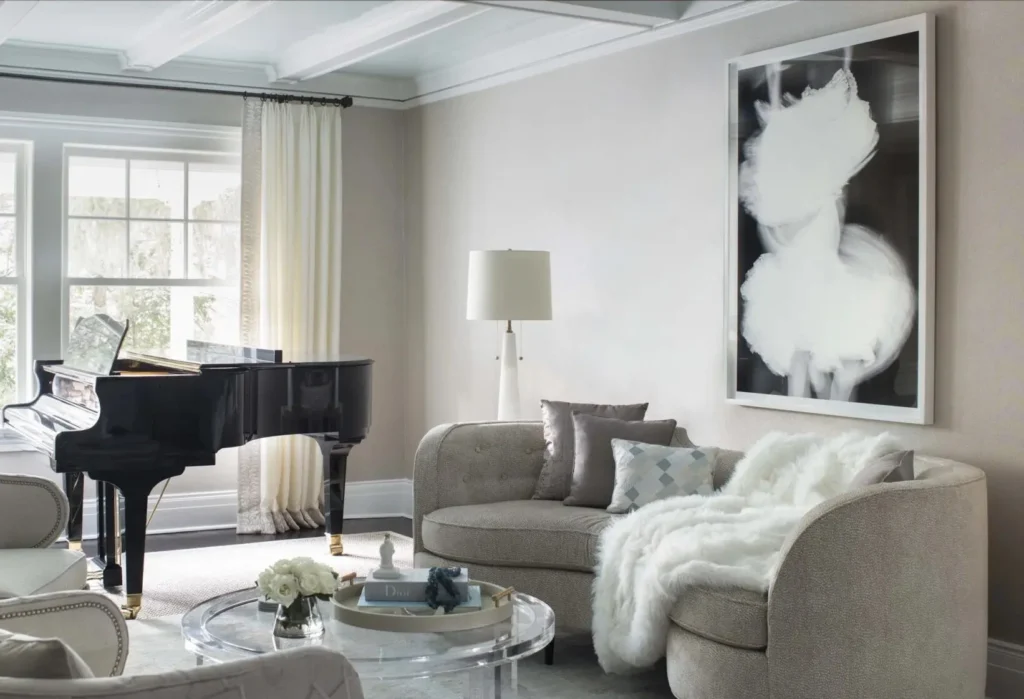 Living room with a curved gray sofa, a black grand piano, large black and white artwork and a floor lamp